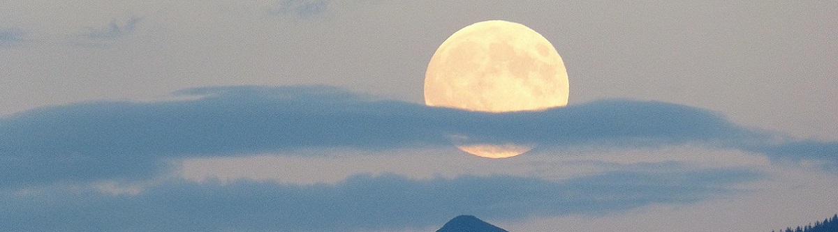 full moon in darkened sky and cloud partially covering it